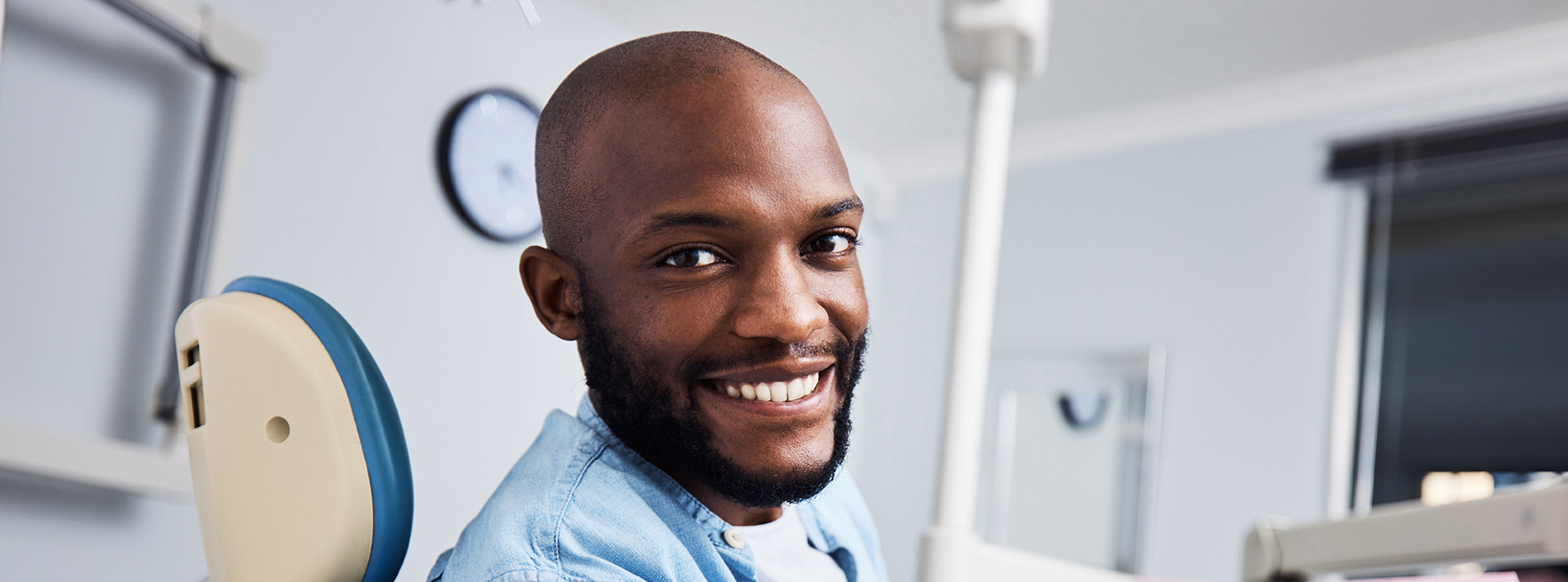 The image shows a person sitting in front of a dental chair, likely in a dental office setting.