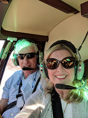 A man and a woman in a small airplane, both wearing headsets and sunglasses.