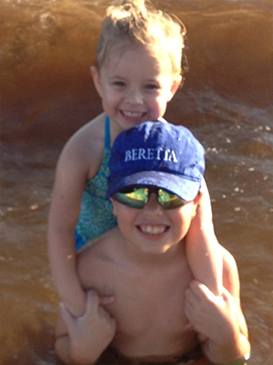 Adult and child in water, adult holding child.
