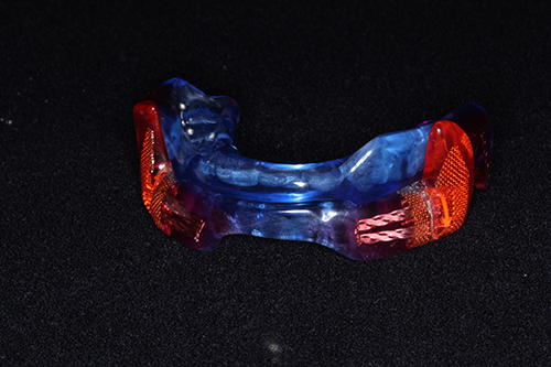 Blue and red plastic sports mouthguard with a clear plastic bite plate.