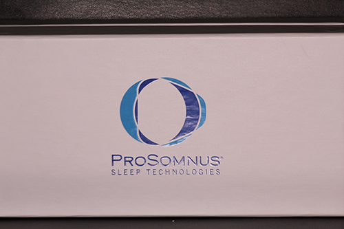 The image shows a logo with the letters  Q  and  O  in blue, with a design that resembles an eye or a target, inside a white box with a black border. Below the logo is a line of text that reads  PROSOMNUS Sleep Technologies.