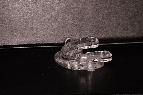 Transparent bracelet with clear crystals, resting on a dark surface.