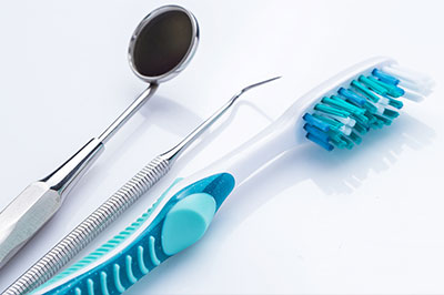 Dental tools and a toothbrush with blue bristles on a white surface.