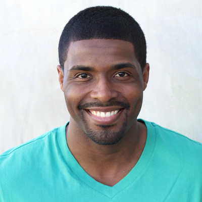 An elderly couple smiling and embracing each other outdoors.