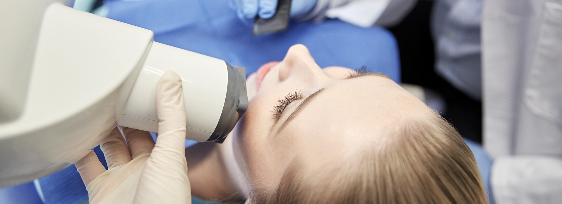 An individual receiving dental care, with a dental practitioner using a magnifying device to examine their teeth.