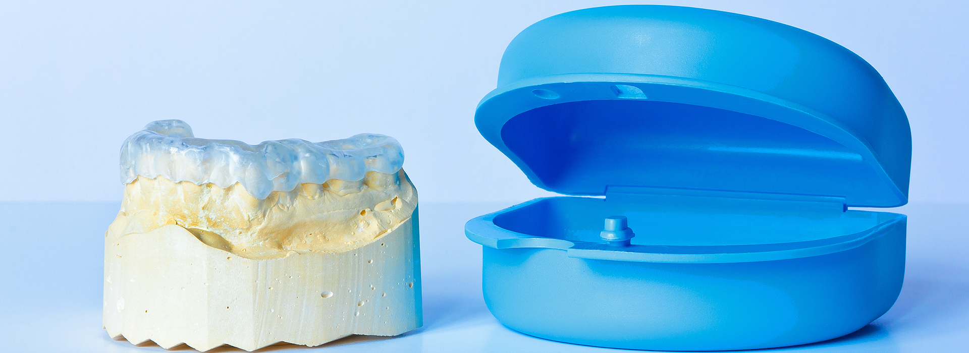 The image displays a pair of blue dental implants and a yellow crown, both against a white background.