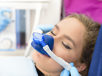 The image shows a person receiving oxygen therapy using a nasal cannula, with the assistance of medical professionals.