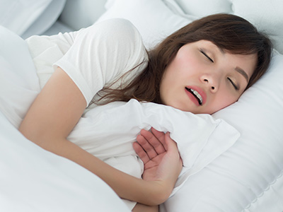 A woman asleep in bed with a pillow over her face.