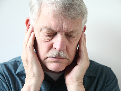 An elderly man with his hand on his face, possibly in pain or discomfort.